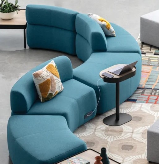 HON SoCo modular lounge seating in teal upholstery arranged in an S curve with a powered laptop table