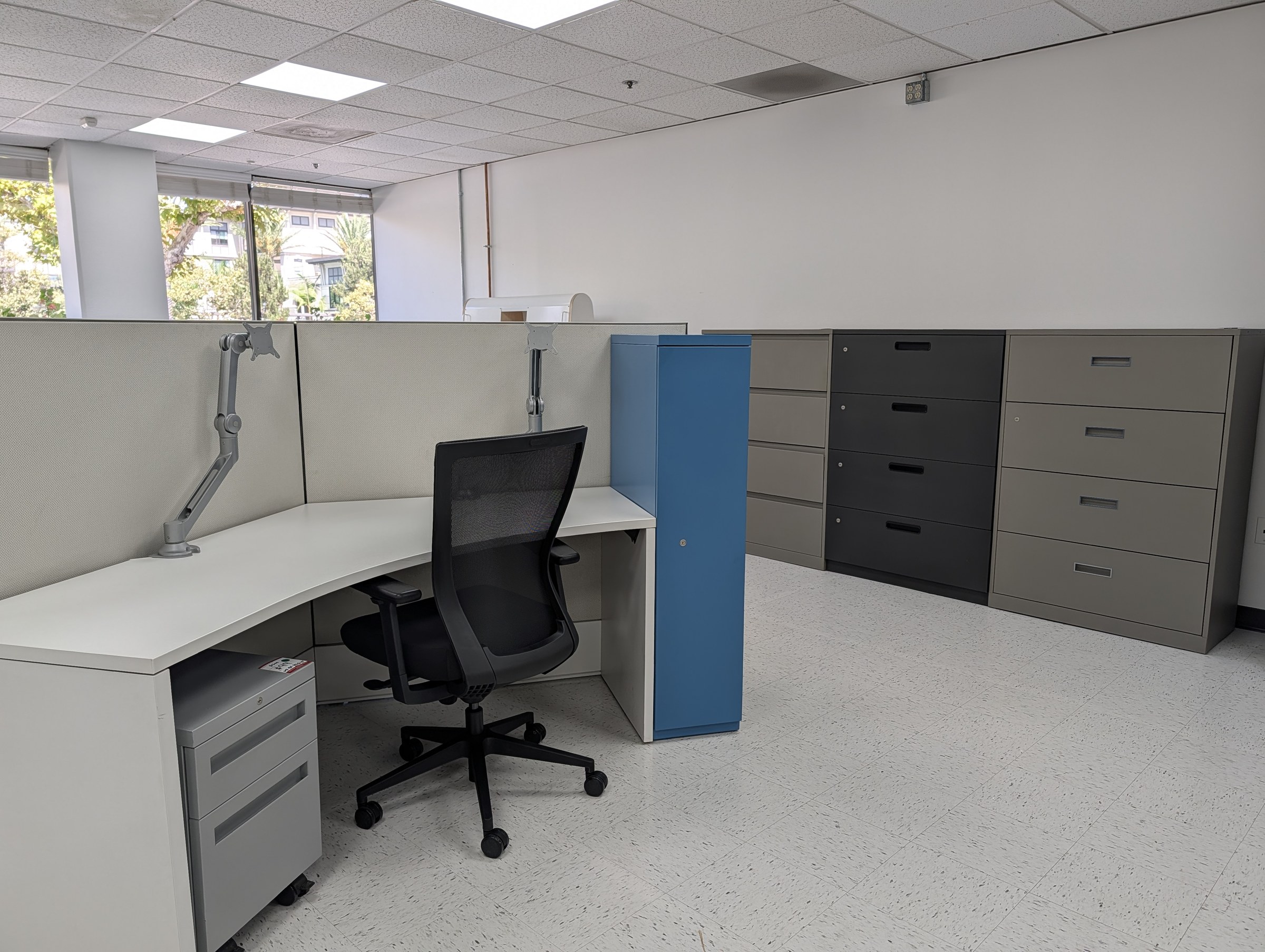 Lateral filing cabinets lined up beside a corner workstation with a mesh task chair in the Irvine showroom