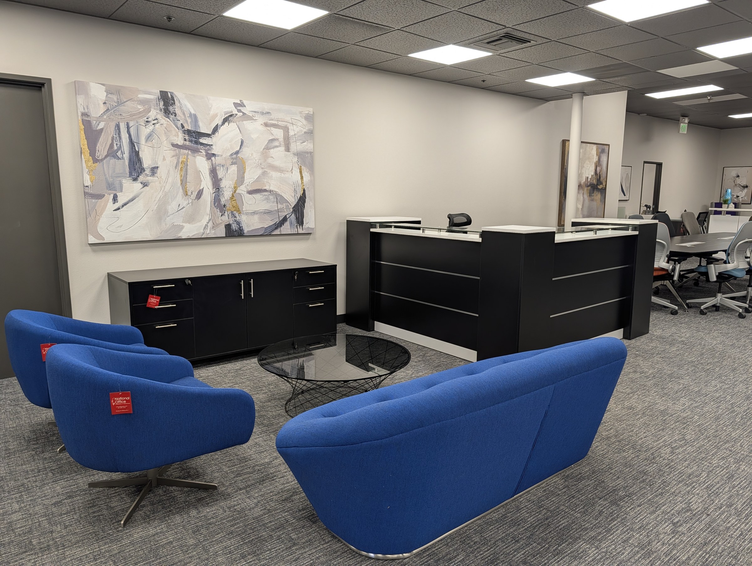 Reception desk display with blue lounge seating and a conference area beyond, in the Irvine showroom